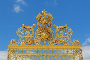 Versay Şatosu 'nun altın süslü kapısının yakın görüntüsü ve arka planda mavi gökyüzü - Versailles, Fransa