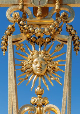 XIV. Louis 'in sembolü Güneş Kralı (Roi Soleil) arka planda mavi gökyüzü olan Versay Şatosu' nun altın kapısında - Versailles, Fransa
