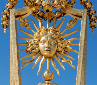 XIV. Louis Sembolü 'nün (Roi Soleil) arka planında mavi gökyüzü olan Versay Şatosu' nun altın kapısı - Versailles, Fransa