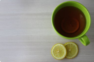 Limonlu bir fincan sıcak çay. Soğuk algınlığı ve grip tedavisi. Grip ilacı, termometre, hap ve kağıt mendil.