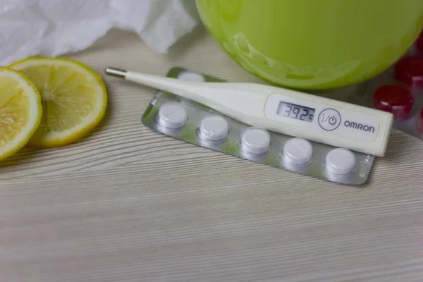 Limonlu bir fincan sıcak çay. Soğuk algınlığı ve grip tedavisi. Grip ilacı, termometre, hap ve kağıt mendil.