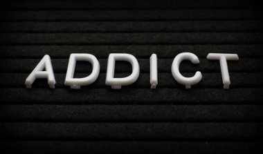 The words Addict in white plastic letters on a black letter board