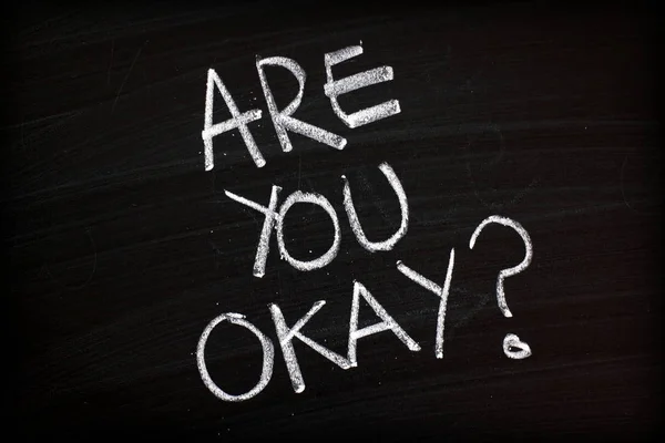 The question Are You Okay written by hand in white chalk on a blackboard