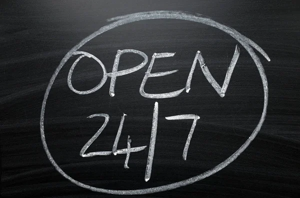 Open twenty four hours by seven written by hand in white chalk on a blackboard sign