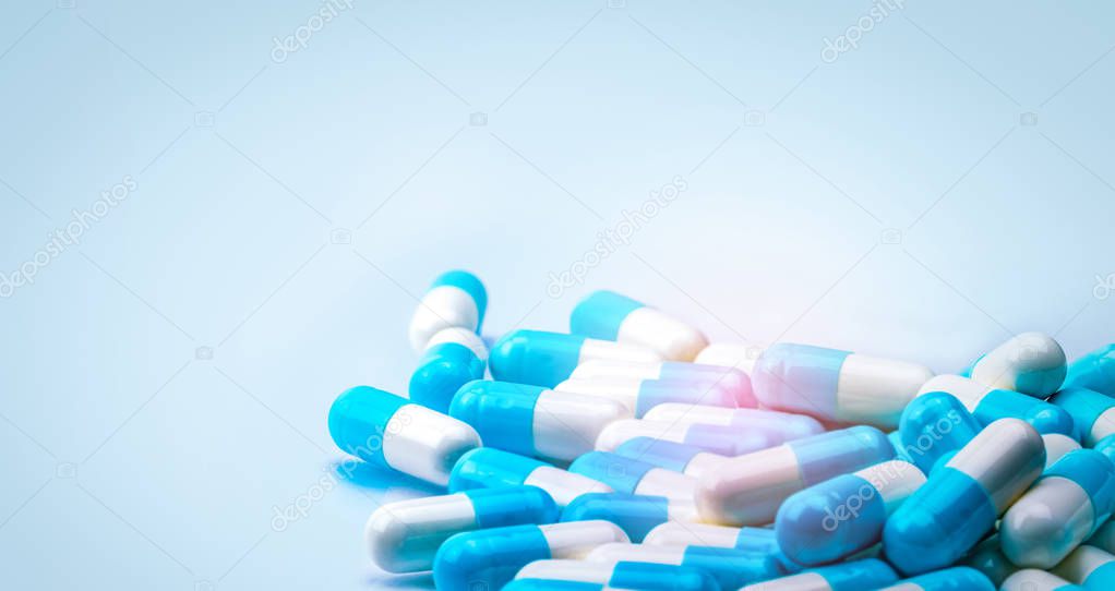 Selective focus on blue and white capsules pill spread on white background with shadow. Global healthcare concept. Antibiotics drug resistance. Antimicrobial capsule pills. Pharmaceutical industry.