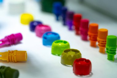 Seçici odak plastik şişe kapağı yiyecek ve içecek ürün farklı tür. Beyaz masa yeşil, sarı, kırmızı, pembe, turuncu, mavi ve mor Kapak kapatma. Modern tasarım plastik şişe kapağı.  