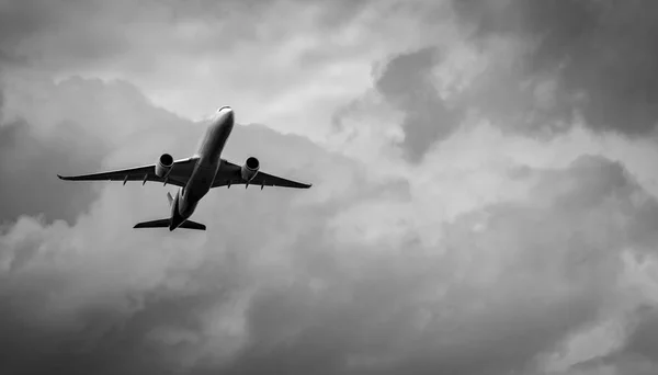 Commercial airplane on grey sky and clouds with copy space. Failed vacation. Hopeless and despair concept. Moody sky and transport plane. Sad emotional scene. Background of aircraft flight.