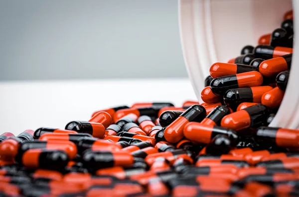 Capsules pill spilled out from white plastic bottle container. Prescription drug. Antibiotics drug resistance. Antimicrobial capsule pills. Pharmaceutical industry. Pharmacy background. Antimicrobial.