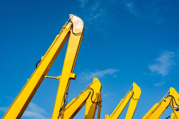 Yellow backhoe with hydraulic piston arm against clear blue sky. Heavy machine for excavation in construction site. Hydraulic machinery. Huge bulldozer. Heavy industry