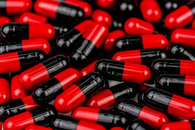 Kırmızı-siyah kapsül hap yığını. Antibiyotik direnci. Uyuşturucu kullanımı ile makul. Küresel sağlık kavramı. Antibiyotik ilaç direnci. Antimikrobiyal kapsül hap. İlaç endüstrisi.