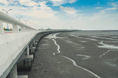 Eğri sahil beton yolu yol çamur Beach mavi gökyüzü ve bulutlar ile daha düşük su ile. Yol yolculuk seyahat. Yaz yolculuk tropikal çimento kiraz kuşu köprüsünde. Doğa arka plan.