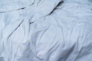 Beyaz keten battaniye otel yatak odasında. Sabah uyanma sonra pis beyaz battaniye detayını kapatın. Rahat yatak yumuşak beyaz yorgan ile. Kaliteli ev kavramı yatak takımları iyi uykular.