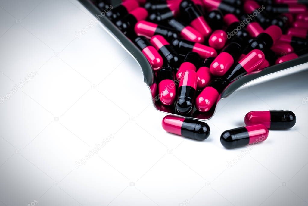 Pink-black capsule pills on drug tray. Antibiotics drug resistance. Global healthcare. Antimicrobial capsule pills. Pharmacy background. Antibiotic drug use with reasonable. Pharmaceutical industry.