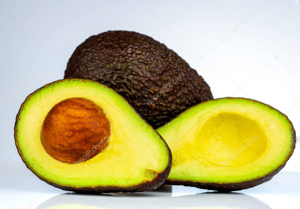 Avocado with seed isolated on white background. Source of omega 3 from natural food. Healthy food for baby. Half pieces of avocados arranged with beautiful pattern. Organic food for vegetarian.