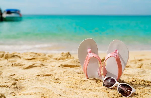 Rosa och vita sandaler, solglasögon på sandstrand vid havet. Casual mode stil flipflop och glasögon på havsstranden. Sommarlov på tropical beach. Kul semesterresor på sandstrand. Sommartid. — Stockfoto
