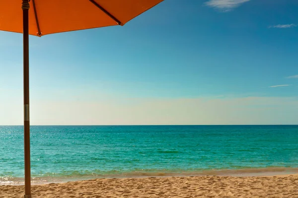 Orange beach paraply på gyllene sandstrand vid havet med smaragd gröna havet vatten och blå himmel och vita moln. Sommarlov på tropiskt paradis strand koncept. Skyline mellan hav och himmel. — Stockfoto