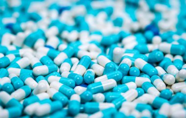 Selective focus on pile of blue and white antibiotic capsule pill. Pharmaceutical production. Global healthcare. Antibiotics drug resistance. Antimicrobial capsule pills. Pharmaceutical industry. clipart