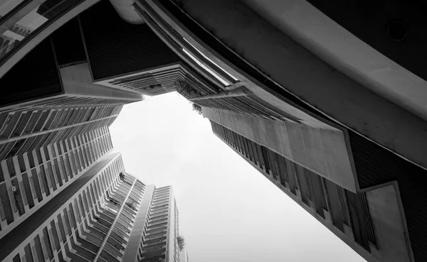 Blick von unten auf Wolkenkratzer vor grauem Himmel und Wolken. Blick nach oben in einem Mehrfamilienhaus in der Stadt. Immobilien und Unternehmensbau. Geschossiges Wohnhaus. Eigentumswohnung. — Stockfoto