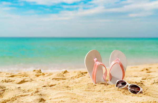 Rosa och vita sandaler, solglasögon på sandstrand vid havet. Casual mode stil flipflop och glasögon. Sommarlov på tropical beach. Kul semesterresor på sandstrand. Sommartid. Sommaren vibes. — Stockfoto