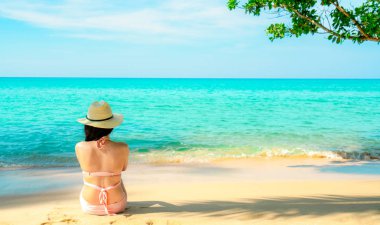 Arkadan görünüşü mutlu genç Asyalı kadın pembe mayo ve hasır şapka rahatlatıcı ve tatil tropik cennet plaj tatil keyfini çıkarın. Yaz tatil moda kız. Güzellik seksi modeli. Yaz vibes.