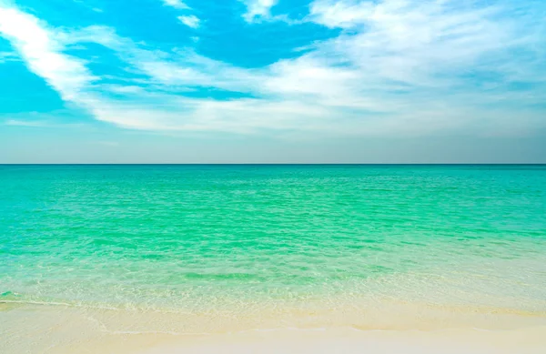 Playa de arena dorada junto al mar con agua de mar verde esmeralda y cielo azul y nubes blancas. Vacaciones de verano en concepto de playa paraíso tropical. Onda de agua salpicada en la playa de arena. Vibraciones de verano. — Foto de Stock