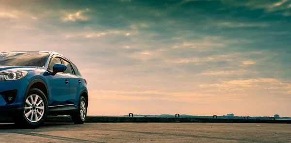 Blauwe compacte Suv auto met sport en modern design geparkeerd op betonnen weg door de zee. Hybride en elektrische auto technologie concept. Parkeerplaats auto. Auto-industrie. Auto zorg dienstverleningsconcept. — Stockfoto