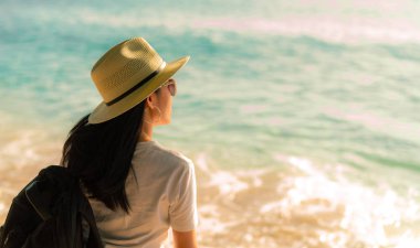 Arkadan görünüşü hasır şapka ve sırt çantası ile rahat tarzı moda mutlu genç Asyalı kadın. Sakin ol ve tropik cennet plaj tatil keyfini çıkarın. Yaz vibes. Rahatlatıcı ve tropikal plaj zevk.