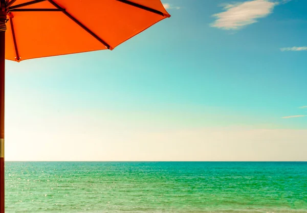 橙色沙滩伞在金色的沙滩上, 海边有翠绿的海水, 蓝天和白云。暑假对热带天堂海滩的概念。海与天之间的天际线. — 图库照片