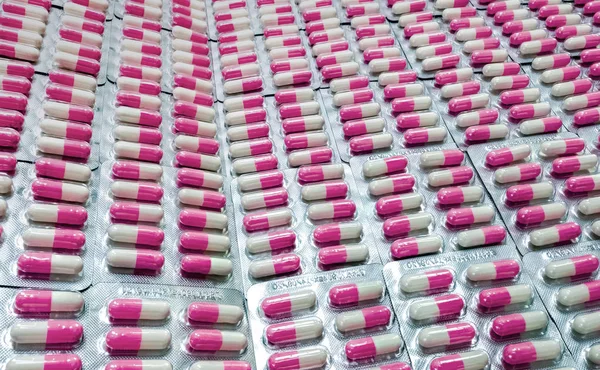 Closeup pink-white antibiotic capsule pills in blister pack. Antibiotic drug resistance. Pharmaceutical industry. Global healthcare. Pharmacy background. Pharmaceutical product. Amoxicillin capsule.