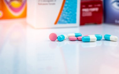 Round pink tablets pill and white-blue capsule pills on blurred background of drug packaging. Painkiller medicine. Drug use for treatment migraine headache. Pharmacy product. Pharmaceutical industry. clipart