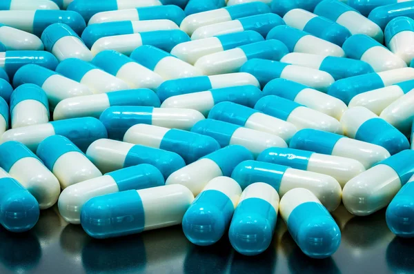 La píldora de la cápsula antibiótica azul-blanca se propagó en la bandeja de acero inoxidable. Concepto de salud global. Resistencia a los antibióticos. Pastillas de cápsulas antimicrobianas. Industria farmacéutica. Textura de cápsula . — Foto de Stock