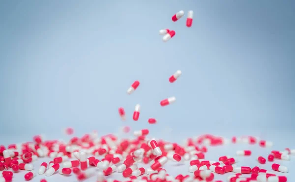 Selective focus on pink-white capsule pill fall down to white table. Antibiotic drug use with reasonable. Antibiotic drug resistance. Pharmaceutical industry. Antimicrobial drug market. — Stock Photo, Image