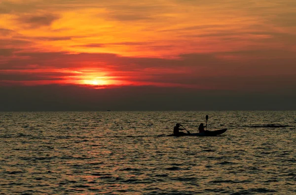 Silhueta de casal estão de caiaque no mar ao pôr-do-sol. Caiaque no mar tropical ao pôr do sol. Casal romântico viajar em férias de verão. Atividades de aventura de casais românticos. Belo céu do pôr do sol . — Fotografia de Stock