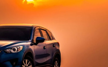 Mavi kompakt Suv araç spor ve modern tasarımı ile akşam günbatımında denizin kenarında beton yolda park etmiş. Hibrit ve elektrikli otomobil teknoloji kavramı. Araba park yeri. Otomotiv Sanayi. 