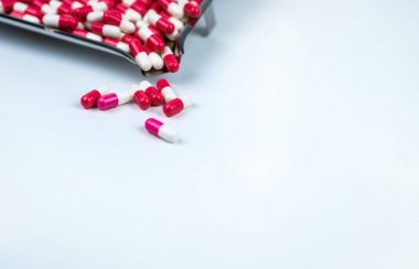 Beyaz masa ve bulanık paslanmaz çelik ilaç tepsisi üzerinde pembe-beyaz ve kırmızı-beyaz kapsül. Sevgililer Günü konsepti için aşk hapları. İlaç endüstrisi. Antibiyotik kapsül hapları. Olağanüstü haplar.