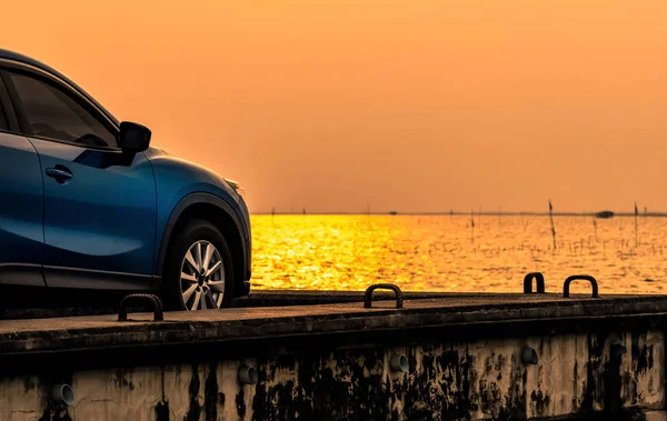 Blue compact SUV car with sport and modern design parked on concrete road by the sea at sunset. Environmentally friendly technology. Electric car technology and business. Hybrid auto and automotive. — Stock Photo, Image