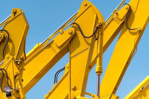 Yellow backhoe with hydraulic piston arm against clear blue sky. Heavy machine for excavation in construction site. Hydraulic machinery. Huge bulldozer. Heavy machine industry. Mechanical engineering.
