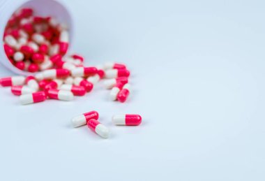 Pembe ve beyaz kapsül ler beyaz plastik şişe kabından döküldü. Küresel sağlık kavramı. Antibiyotikler ilaç direnci. Antimikrobiyal kapsül hapları. İlaç endüstrisi. Eczane.