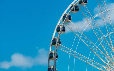 Mavi gökyüzü ve beyaz bulutlara karşı closeup modern Dönme dolap. Tatilde eğlence ve eğlence için lunaparkta dönme dolap. Eğlence içinde dönme dolap modern inşaat. Eğlenceli festival.