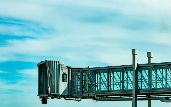 Jet bridge dopo linea aerea commerciale decollare in aeroporto contro cielo blu e nuvole bianche. Ponte di imbarco passeggeri degli aerei attraccato. Volo di partenza della compagnia aerea internazionale. Ponte a getto vuoto . — Foto Stock