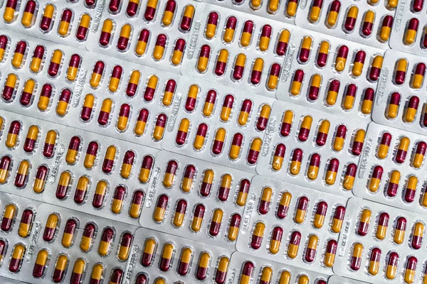 Industria farmaceutica. Capsule rosso-gialle in blister. Imballaggio farmaceutico. Prodotto farmaceutico. Sanità globale. Uso di droghe in ospedale. Tendenze del mercato della droga. Bilancio e politica sanitaria . — Foto Stock