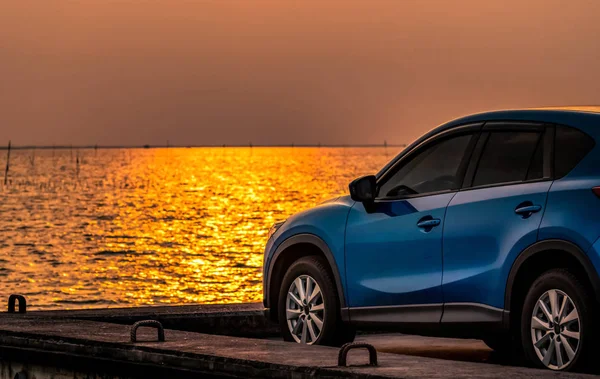 Kék kompakt Suv autó sport és a modern design parkol betonút a tengerparton naplementekor. Környezetbarát technológia. Elektromos autó technológiai és üzleti. Hibrid és autóipari. — Stock Fotó