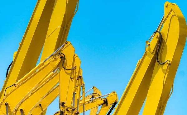 Retroescavadeira amarela com braço de pistão hidráulico contra céu azul claro. Máquina pesada para escavação no canteiro de obras. Máquinas hidráulicas. Um enorme bulldozer. Indústria de máquinas pesadas. Engenharia mecânica. — Fotografia de Stock