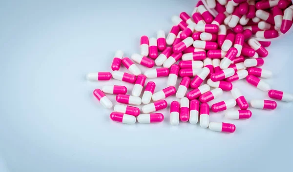 Cápsulas rosadas y blancas de la píldora derramada del envase de plástico blanco. Concepto de salud global. Resistencia a los antibióticos. Pastillas de cápsulas antimicrobianas. Industria farmacéutica. Farmacia . — Foto de Stock