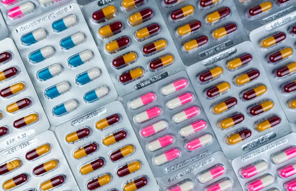 Top view of colorful antibiotic capsule pills in blister pack. Antibiotic drug resistance. Pharmaceutical industry. Pharmacy drug store background. Global health care.  Antimicrobial capsule pills.