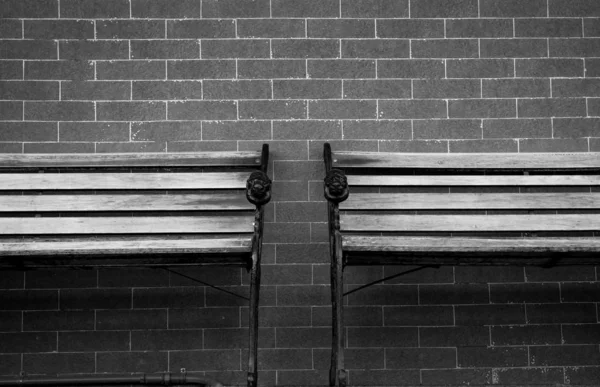 Banco de madera de pareja vacía sobre fondo de pared de ladrillo gris. Concepto de emoción solitaria y melancólica. Antecedentes de tristeza, tristeza, tranquilidad y silencio. Esperando a que alguien llene la silla de madera vacía . — Foto de Stock