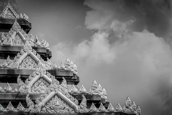 Closeup detail of temple in Thailand. Art pattern. Traditional Thai style sculpture against clouds and sky. Black and white scene of temple detail. Background for sad and death. Buddhist building. — Stock Photo, Image