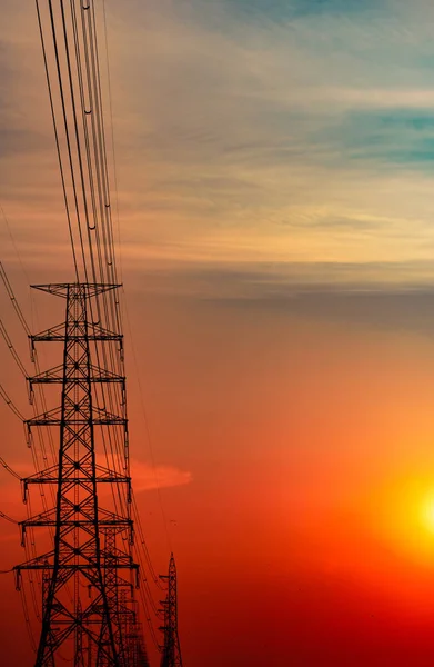 Hoogspanning elektrische pool en transmissielijnen in de avond. Elektriciteitsmasten bij zonsondergang. Macht en energie. Energiebesparing. Hoogspanningsnettoren met draadkabel bij distributiestation. — Stockfoto