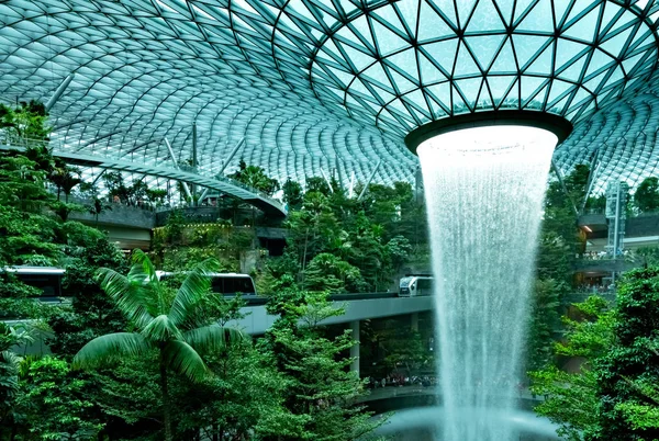 Rain Vortex, Jewel Changi Havaalanı'nda dünyanın en yüksek kapalı şelalesi. Alışveriş merkezinde yeşil orman ve skytrain. Singapur Changi Havaalanı'nda ikonik simgesel yerler. Cam kubbede şelale. 
