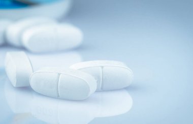Çocuklar veya hamile kadınlar için kalsiyum tabletleri. Bulanık ilaç şişesi arka planda beyaz tablet hapları. Vitaminler ve ek kavramı. İlaç endüstrisi. Eczane ürünleri. Küresel sağlık.